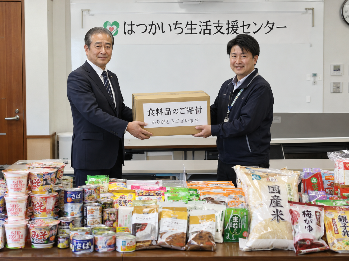 企業の方から男性職員が食品の寄贈を受けるイメージ